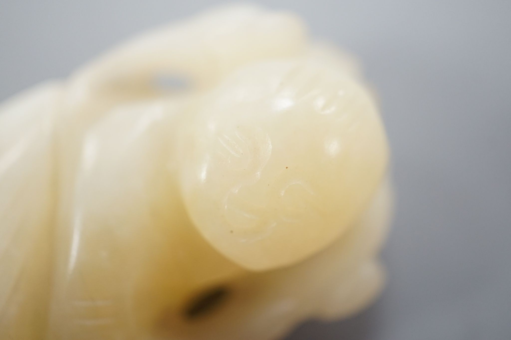 A Chinese bowenite jade carving of a boy with a branch, 5.5 cms high.
